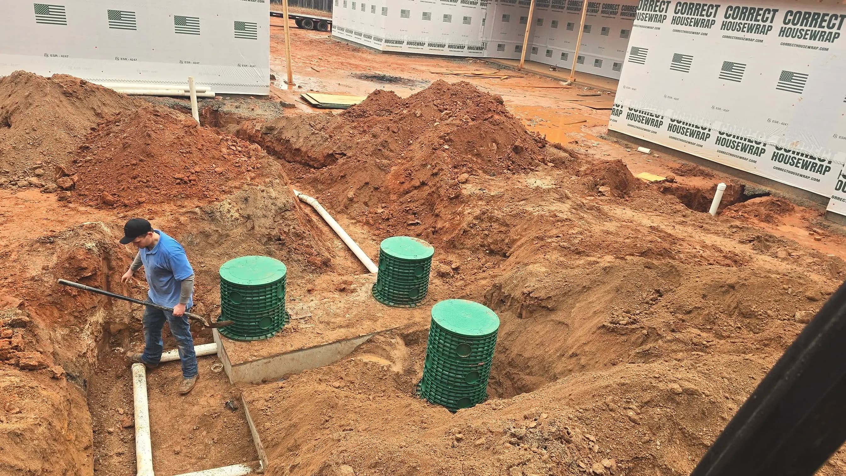 From our job files: a new-construction septic install, three green risers set in Georgia red clay beside the PVC lines; illustrating septic repair for Loganville, Georgia