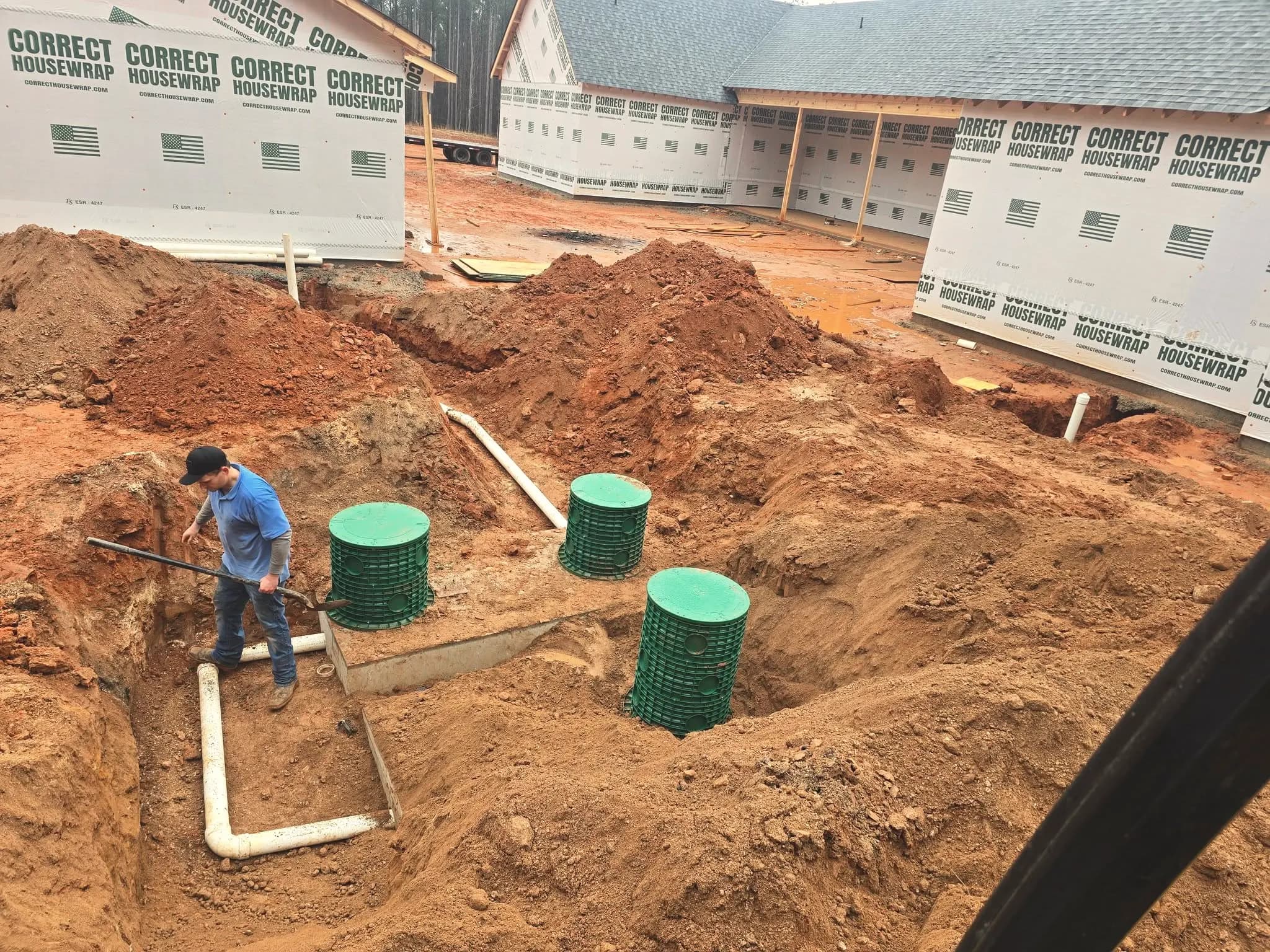 New-construction septic install with risers set in red clay.